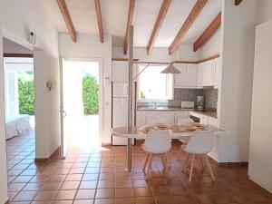cocina con armarios blancos, mesa y sillas en "PARAÍSO 14" Espectacular casa con terrazas, piscina y vistas al mar, en Son Xoriguer
