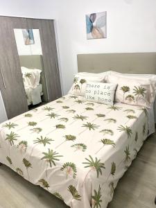 uma cama com uma colcha branca com palmeiras em Blue house 1ª linea playa em Torrevieja