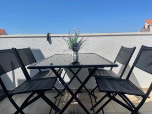 a table and chairs with a vase with flowers on it at Apartment New Chic in Supetar