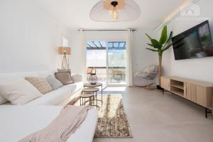 Biały salon z białą kanapą i telewizorem w obiekcie Scandinavian style apartment with sea views in a beachfront urbanisation in Calahonda 15 minutes from center of Marbella! w mieście Sitio de Calahonda
