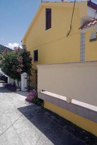ein gelbes Haus mit einem Zaun neben einem Bürgersteig in der Unterkunft Apartments by the sea Barbat, Rab - 4977 in Barbat na Rabu