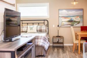 a bedroom with a bed and a table with a television at RainCoast Retreat at Shawnigan Lake! in Shawnigan Lake