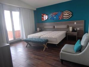 a bedroom with a bed and a couch and a chair at Cortesito santana in Punta Cana