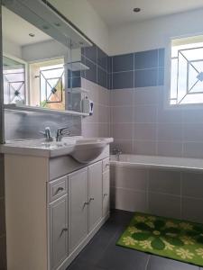 ein Badezimmer mit einem Waschbecken, einer Badewanne und einem Spiegel in der Unterkunft Jolie villa 20min de Lourdes in Asson