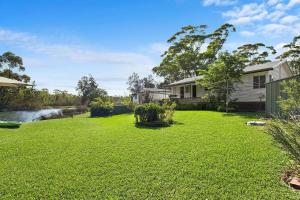 une cour avec une maison et une rivière dans l'établissement Lake Frontage, à Lake Tabourie