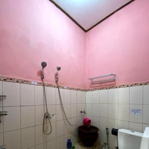 a bathroom with a pink wall and a toilet at Homestay Sente in Munduk