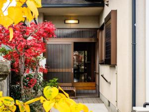 een voordeur van een huis met rode bloemen bij Yanagi-an in Kameoka