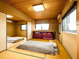 2 bedden in een kleine kamer met houten plafonds bij Yanagi-an in Kameoka