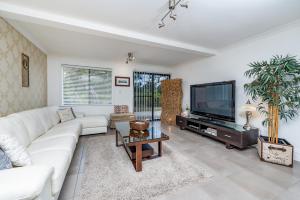 uma sala de estar com um sofá branco e uma televisão em Swan Valley em Upper Swan