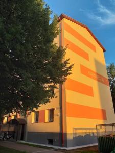 a yellow and orange building with a tree next to it at Rannarajooni holiday apartment in Pärnu