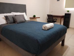 a bed with a blue comforter and a rolled up towel at Departamento México in Tampico