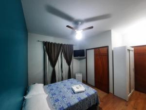 Schlafzimmer mit einem Deckenventilator und einem Bett in der Unterkunft Alvorada Guest House in Caxambu