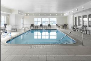uma piscina num quarto de hotel com mesas e cadeiras em Residence Inn Manassas Battlefield Park em Manassas