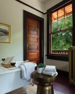 baño con bañera, mesa y ventana en Naramata Inn, en Naramata