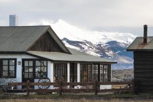 a barn with a snow covered mountain in the background at Bories - Boutique Guest House in Puerto Natales