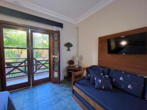 ein Wohnzimmer mit einem blauen Sofa und einem TV in der Unterkunft Suíte 1210 em Flat frente ao mar in Ilhabela