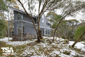 a house in the snow with trees in front of it at Chalet 26 in Thredbo