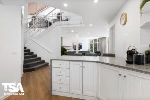 a kitchen with white cabinets and a staircase at Chalet 26 in Thredbo