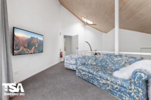 a living room with a couch and a tv on the wall at Chalet 26 in Thredbo