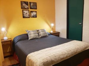 a bedroom with a bed with two lamps and pictures on the wall at Hospedaje Lo de Max in San Carlos de Bariloche