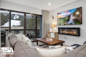 a living room with a couch and a fireplace at Mowamba B2 in Thredbo