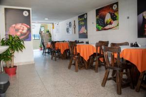 a restaurant with tables and chairs with orange table cloth at Restaurante y Hostal: De La Villa Pa Sumercé in Monguí