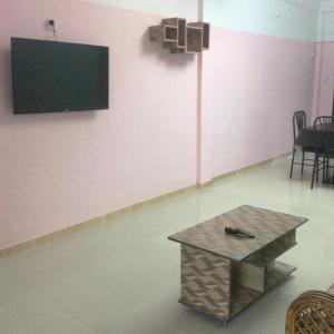 a room with a table and a tv on a wall at ApartmenT - Homestays in Sylhet