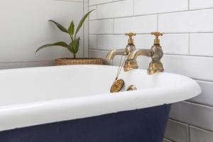 a bathroom sink with two faucets and a plant at Mena-close to Ballarat CBD, self check-in with bath and cot in Ballarat
