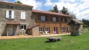 una gran casa de piedra con un banco en el patio en Domaine du Mas du Taillet, en Lanarce