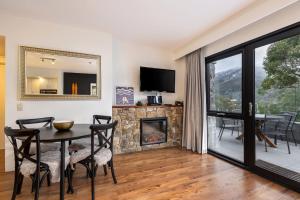 a dining room with a table and a fireplace at Lantern 1 Bedroom Deluxe with hot tub and car park in Thredbo