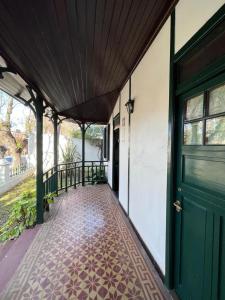 a porch with a green door and a tile floor at Villa Tamen - Colonia in Colonia del Sacramento