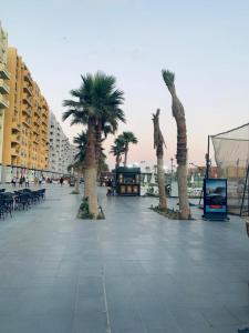 a boardwalk with palm trees and tables and buildings at Prime chalet in Golf Porto Marina resort new Alamein in El Alamein