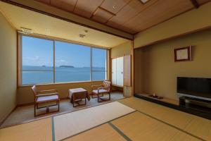 a room with a large window with chairs and a television at Shofuen in Gamagori