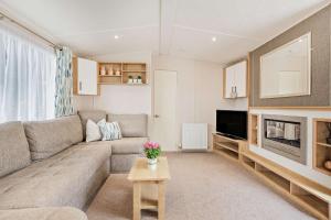 sala de estar con sofá y TV en Maple Brook Lodge Sea Breeze Shorefield, en Lymington