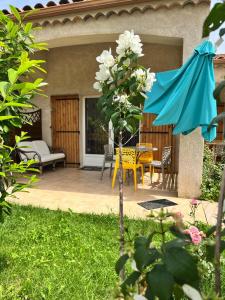 eine Terrasse mit einem blauen Sonnenschirm, einem Tisch und Stühlen in der Unterkunft Le Romulus in Roumoules