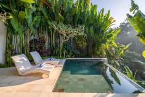 einen Pool inmitten eines Gartens mit zwei Stühlen in der Unterkunft Villa Charles Ubud in Ubud + 4 Fotos