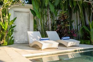 2 sillas sentadas junto a una piscina en Villa Charles Ubud, en Ubud