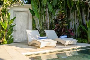 - deux chaises assises à côté de la piscine dans l'établissement Villa Charles Ubud, à Ubud