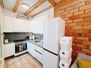 a kitchen with white cabinets and a brick wall at Edificio Amalia Rosina 4ºB in Ourense