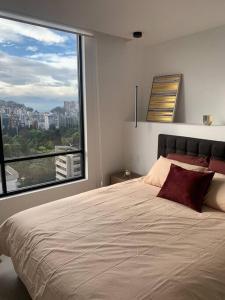 um quarto com uma cama grande e uma janela grande em Confort suite La Carolina em Quito