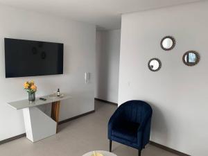 uma sala de estar com uma cadeira azul e uma televisão em Confort suite La Carolina em Quito