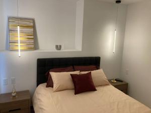 um quarto com uma cama com duas mesas de cabeceira e dois candeeiros em Confort suite La Carolina em Quito