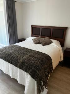 1 dormitorio con 1 cama grande con manta marrón en Departamento El Chiriwe, en Puerto Varas