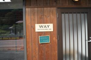 un cartel en la puerta de un edificio en WAY SHIRAKAWAGO - Private, Free Parking and Newly Opened 2022 WAY SHIRAKAWAGO, en Shirakawa