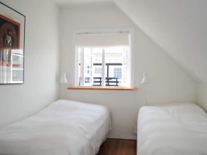 Duas camas num quarto branco com uma janela em Holiday home Svaneke II em Svaneke