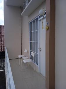 einen Balkon mit weißen Stühlen und einem Fenster in der Unterkunft Ni_Er Guesthouse by Mr.Tsabalala in Panjunan