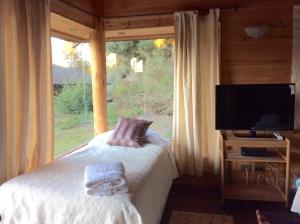 a bedroom with a bed and a large window at Cabañas Playa Linda in Pucón