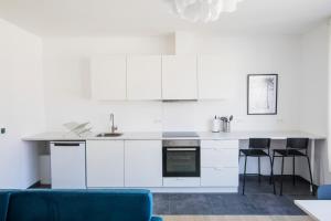 cocina con armarios blancos y sofá azul en Smart Appart - Clmenceau en Bruselas