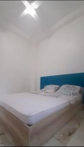 a white bed with a blue headboard and pillows at Appartement T3 Cœur De Ville Patio in Fort-de-France