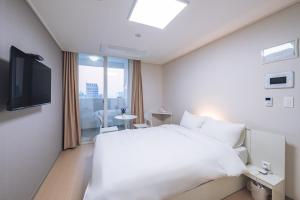 a hotel room with a white bed and a window at Chuncheon Bella Residence in Chuncheon